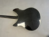 Back of black electric guitar body with glossy finish and visible scratches on gray surface background