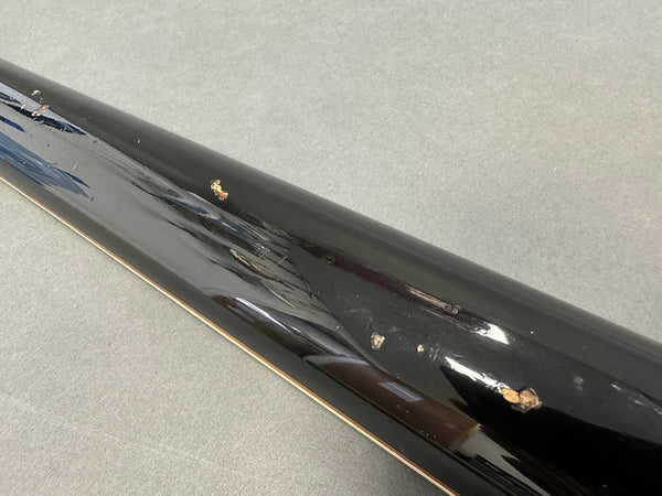 Close-up of black glossy guitar neck with multiple dings and scratches on the back side showing wear and tear