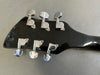 Close-up of black guitar headstock with six chrome tuning pegs showing wear and scratches on gray background