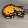Semi-hollow body electric guitar with sunburst finish, dual humbucker pickups, black pickguard, and four control knobs on gray background