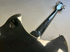 Back view of black electric guitar with glossy finish showing neck and tuning pegs on gray surface
