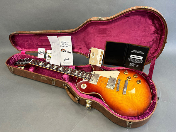 Gibson Les Paul electric guitar sunburst finish with case and warranty documents laid out on gray surface