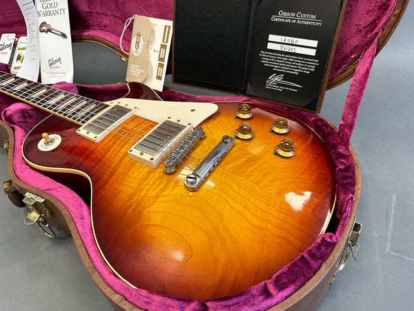 Gibson Les Paul electric guitar with sunburst finish in pink velvet lined hardshell case showing Gibson Gold Warranty and Certificate of Authenticity documents