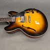 Semi-hollow electric guitar with sunburst finish, dual humbucker pickups, black pickguard, and f-holes on gray background