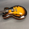 Semi-hollow electric guitar with sunburst finish, two humbucker pickups, and black control knobs on gray background