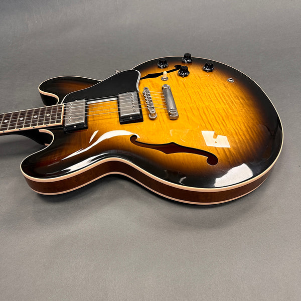 Semi-hollow electric guitar with sunburst finish, two humbucker pickups, and black control knobs on gray background