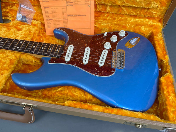 Blue electric guitar with tortoise shell pickguard and white knobs in yellow plush-lined hard case
