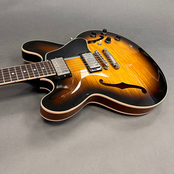Semi-hollow electric guitar with sunburst finish, dual humbucker pickups, and rosewood fretboard on gray background