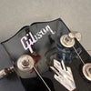 Close-up of black Gibson guitar headstock with silver tuning pegs and mother-of-pearl Gibson logo and inlay detail