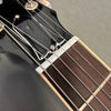 Close-up of electric guitar headstock and fretboard with metal strings and black tuning pegs on gray background