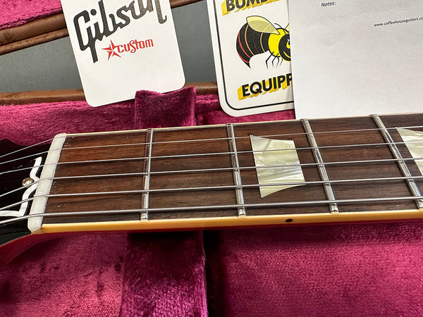 Close-up of Gibson Custom electric guitar rosewood fretboard with mother of pearl block inlays and nickel frets inside a pink velvet guitar case with Gibson Custom and Bumblebee Equipment cards