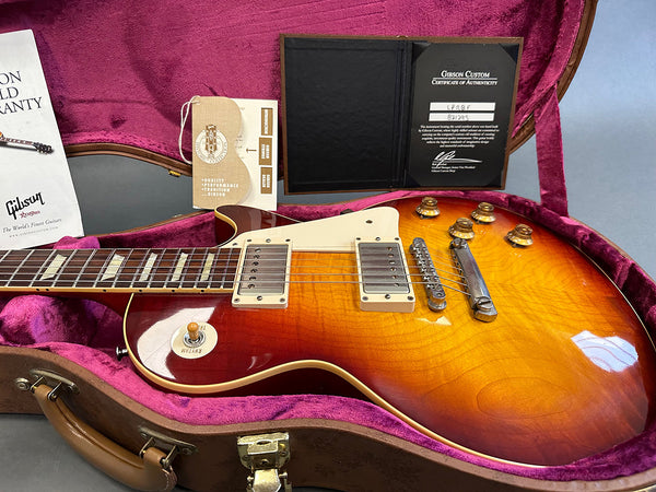 Gibson Les Paul electric guitar in sunburst finish with cream pickguard, humbucker pickups, and gold control knobs, displayed in pink plush-lined hard case with Gibson Custom Certificate of Authenticity and warranty documents.