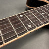Close-up of electric guitar fretboard with mother-of-pearl dot inlays and steel strings on dark wood fingerboard