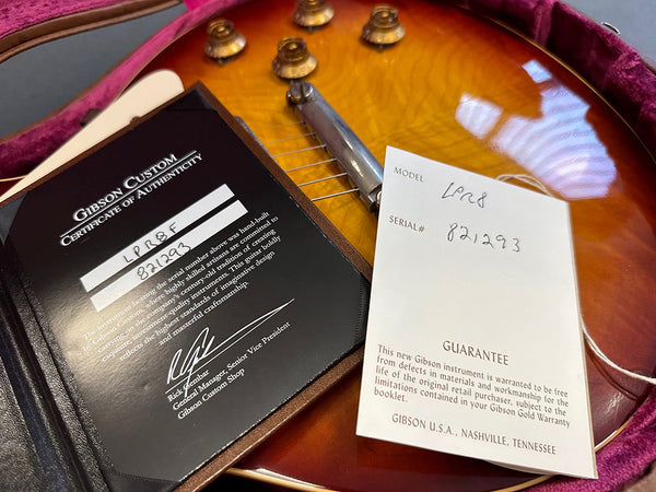 Gibson Custom Certificate of Authenticity and warranty guarantee card on sunburst Gibson guitar with serial number 821293 and model LPR8 displayed in guitar case
