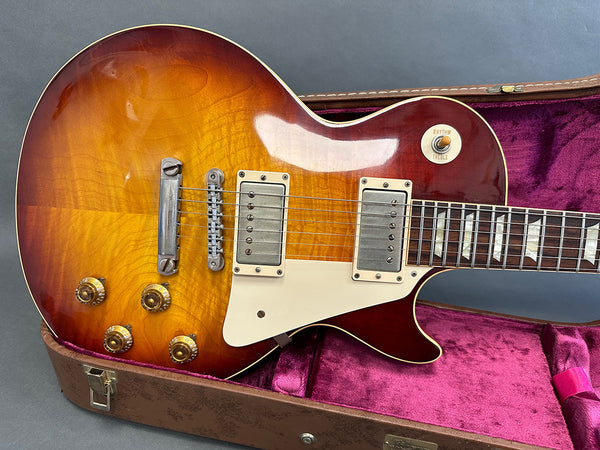 Sunburst finish electric guitar with dual humbucker pickups and four control knobs in open brown hard case with purple plush interior