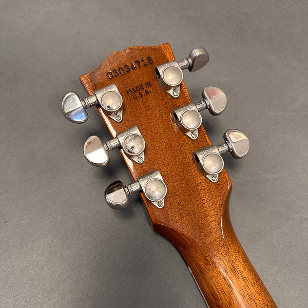 Back of acoustic guitar headstock showing Grover tuning pegs, serial number 09034718, and Made in U.S.A. stamp on natural wood finish