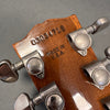 Close-up of guitar headstock back showing Grover tuning pegs and serial number 03034718 stamped on wood with "Made in U.S.A." text