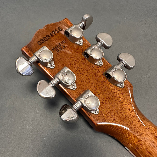 Back of acoustic guitar headstock showing Grover tuning machines and serial number stamped on wood, made in USA detail