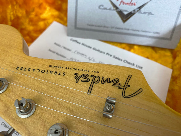 Close-up of Fender Stratocaster guitar headstock with tuning pegs and Coffee House Guitars pre-sales check list in the background