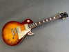 Gibson Les Paul electric guitar with sunburst finish and cream pickguard on gray background