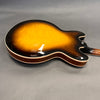 Back view of sunburst finish semi-hollow electric guitar with wood grain and cream binding on grey background
