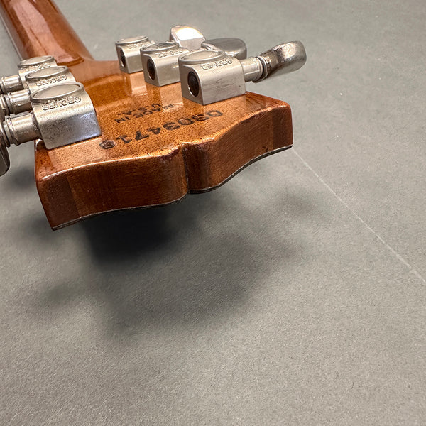 Close-up of wooden guitar headstock with Grover tuning pegs and visible serial number on the back of the neck