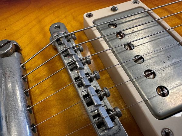 Close-up of electric guitar bridge and metal pickup on sunburst wood body with steel strings