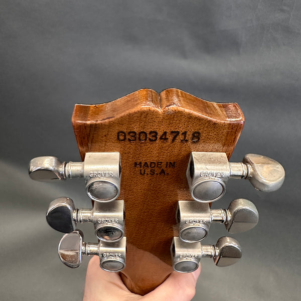 Close-up of guitar headstock back showing serial number 03034719, Made in USA stamp, and six Grover tuning pegs on natural wood finish guitar neck