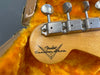 Close-up of Fender Custom Shop guitar headstock with vintage tuning pegs inside orange plush-lined guitar case