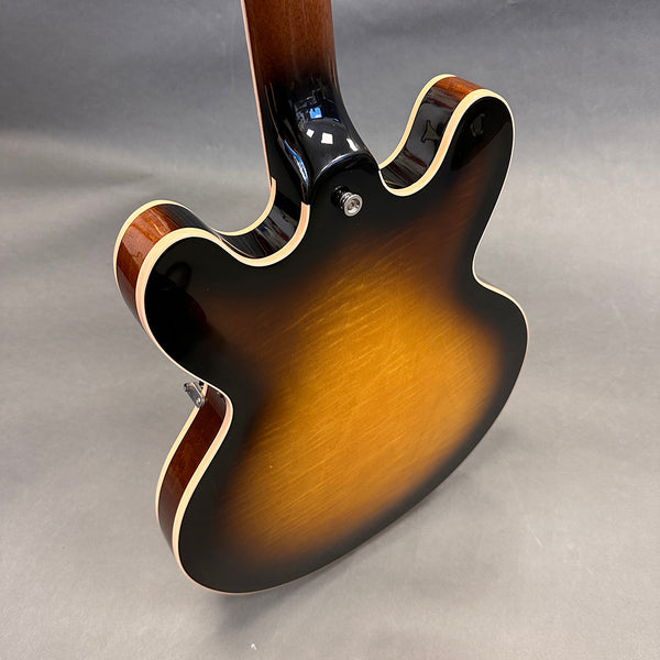 Back of semi-hollow body electric guitar with sunburst finish and cream binding, displayed on gray background
