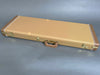 Hard shell tan guitar case with brown leather handle and brass latches on gray background