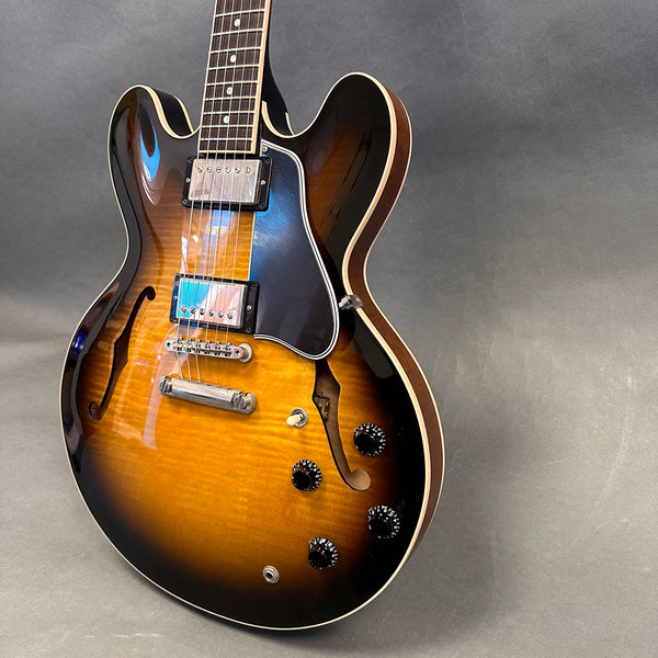 Semi-hollow electric guitar with sunburst finish, dual humbucker pickups, black pickguard, and four control knobs on gray background
