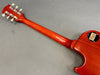 Back view of red Gibson Les Paul Custom electric guitar neck and headstock with tuning pegs and serial number on gray background
