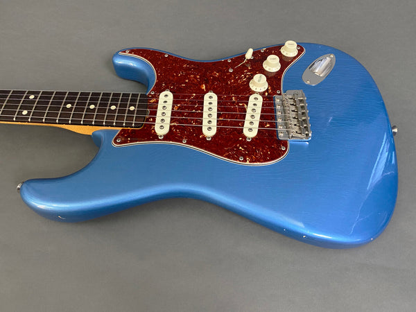 Blue electric guitar with tortoiseshell pickguard and three single-coil pickups on gray background