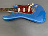 Blue solid body electric guitar with tortoise shell pickguard, three single-coil pickups, white control knobs, and rosewood fretboard on gray background.