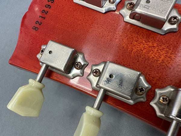 Close-up of vintage Kluson Deluxe tuning pegs with ivory-colored buttons on mahogany guitar headstock with serial number 821293.