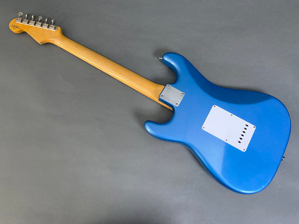 Electric guitar with blue body and natural wood neck shown from the back on a gray background