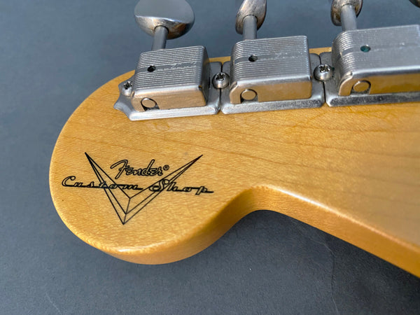 Close-up of Fender Custom Shop guitar headstock with vintage tuning pegs and logo on natural wood finish
