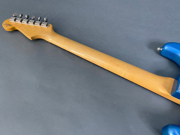 Maple neck and tuning pegs of electric guitar with blue body on gray background