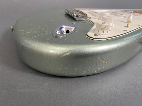 Close-up of worn green electric guitar body with white control knobs and visible scratches and paint wear from Coffee House Guitars