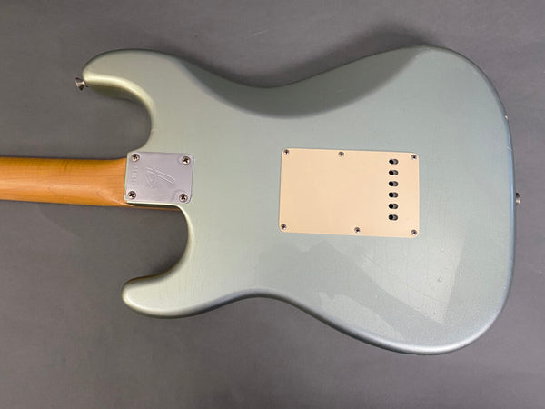 Back view of silver Fender electric guitar body with maple neck and white plastic backplate on gray background