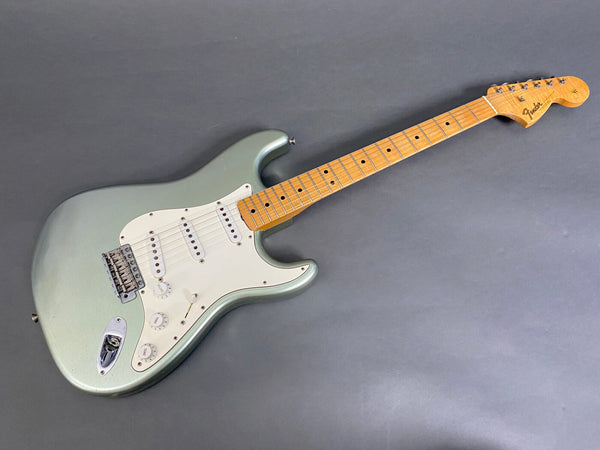 Fender Stratocaster electric guitar in vintage green with maple neck and three single-coil pickups on gray background