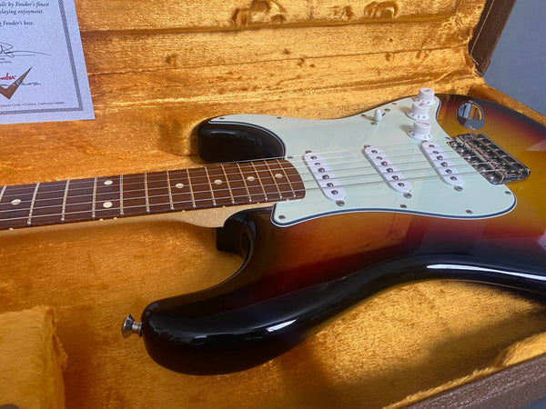 Vintage sunburst Fender Stratocaster electric guitar with rosewood fretboard and white pickguard in a plush gold-lined hard case