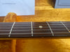 Close-up of guitar fretboard with metal frets and dot inlay, resting on orange plush guitar case lining at Coffee House Guitars