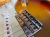 Close-up of Fender electric guitar bridge and strings on sunburst finish body with white volume and tone control knobs