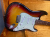 Electric guitar with sunburst finish and white pickguard in orange guitar case interior