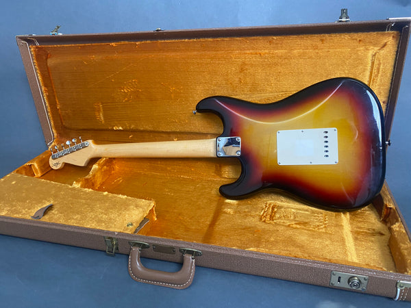 Sunburst electric guitar with maple neck resting in vintage orange plush-lined brown hardshell case shown from the back.
