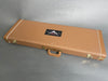 Brown vintage-style hard guitar case with white stitching and gold latches featuring a Fender Custom Shop logo on the lid
