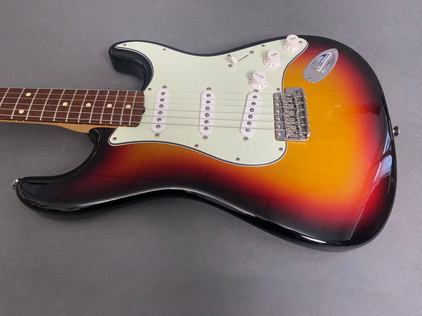 Sunburst electric guitar body with three white single-coil pickups and white control knobs on gray background.