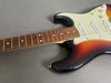 Sunburst electric guitar body with white pickguard and rosewood fretboard on gray background